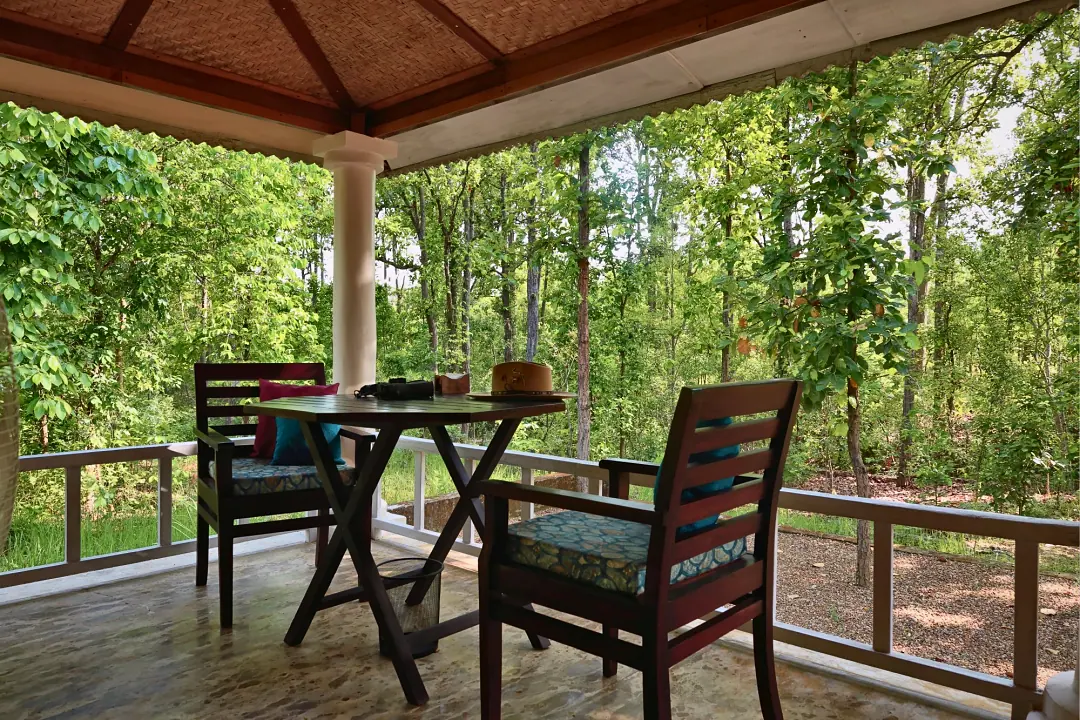 Chairs and a small table on the Bungalow's veranda, facing the forest