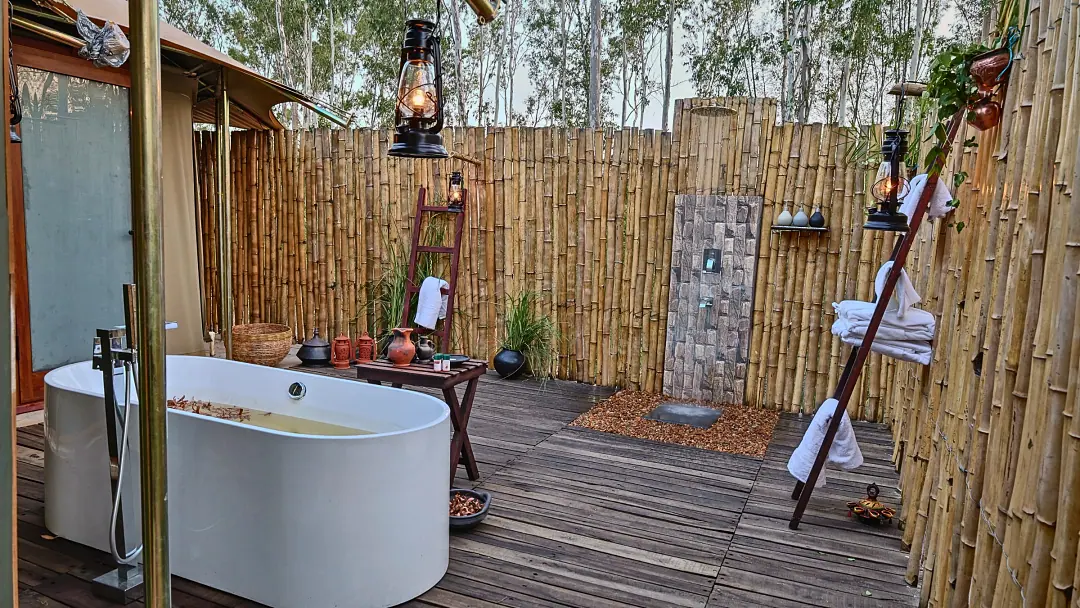 A freestanding bathtub on a bamboo-screened deck open to the sky