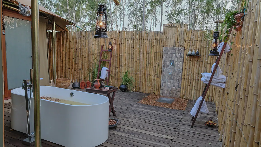 A freestanding bathtub on a bamboo-screened deck open to the sky