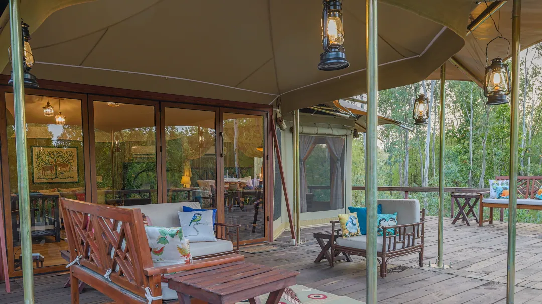 The Chief's Tent veranda with lanterns, a planter's chair and a sofa beside the glass doors