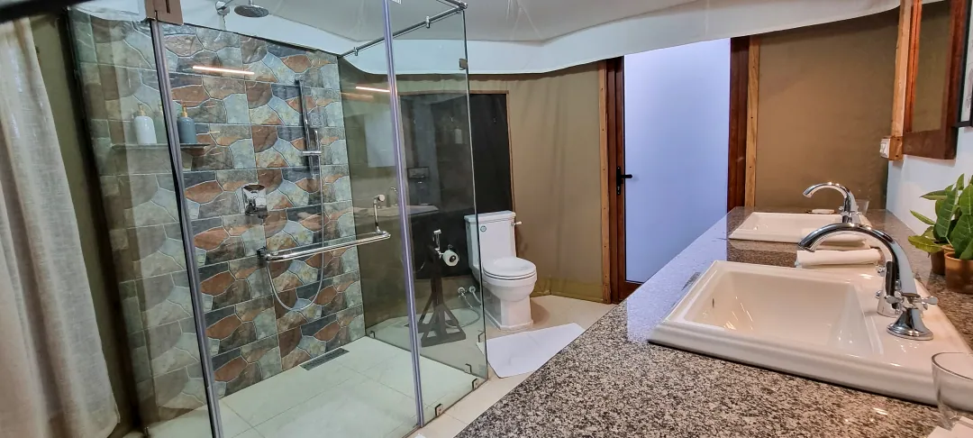 The Chief's Tent bathroom with a glass shower and stone-tiled wall