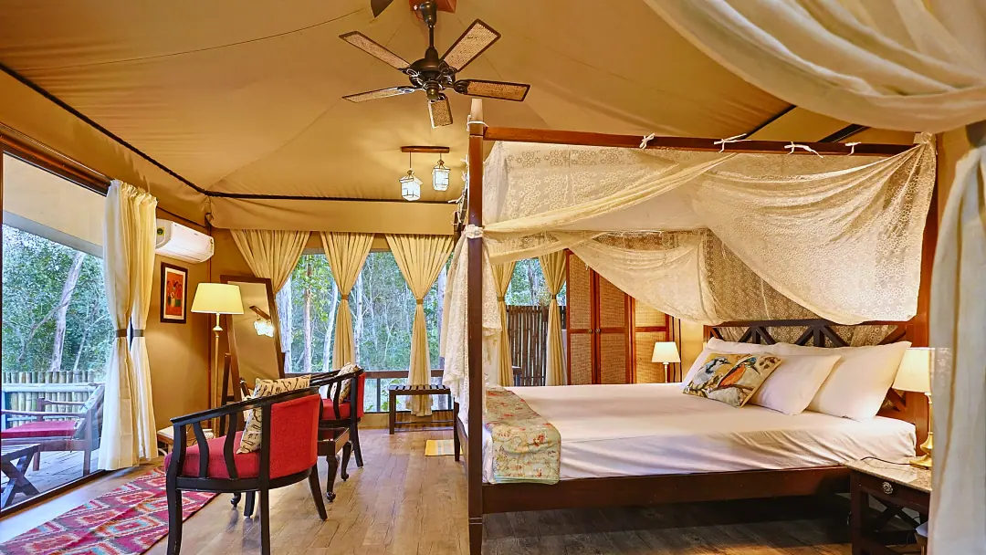 The four-poster bed in the King's Tent with red chairs and forest views