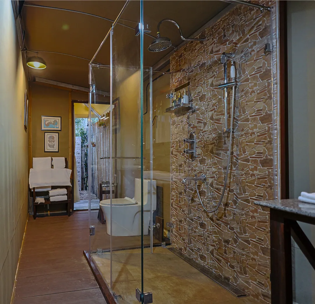 The King's Tent bathroom with a glass shower and a stone wall