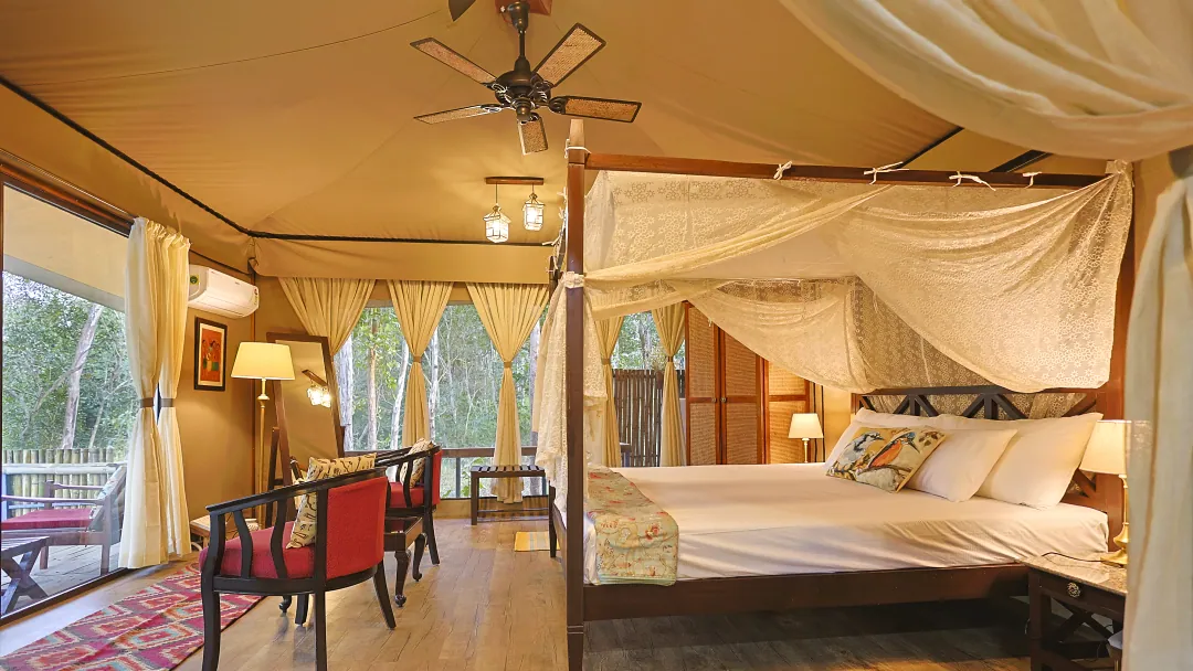 The four-poster bed in the King's Tent with red chairs and forest views